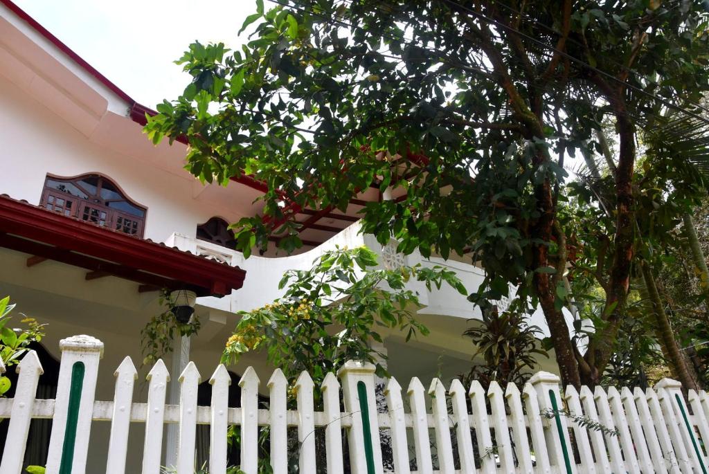 a white picket fence in front of a house at Ellagama Village Bungalow in Diyatalawa