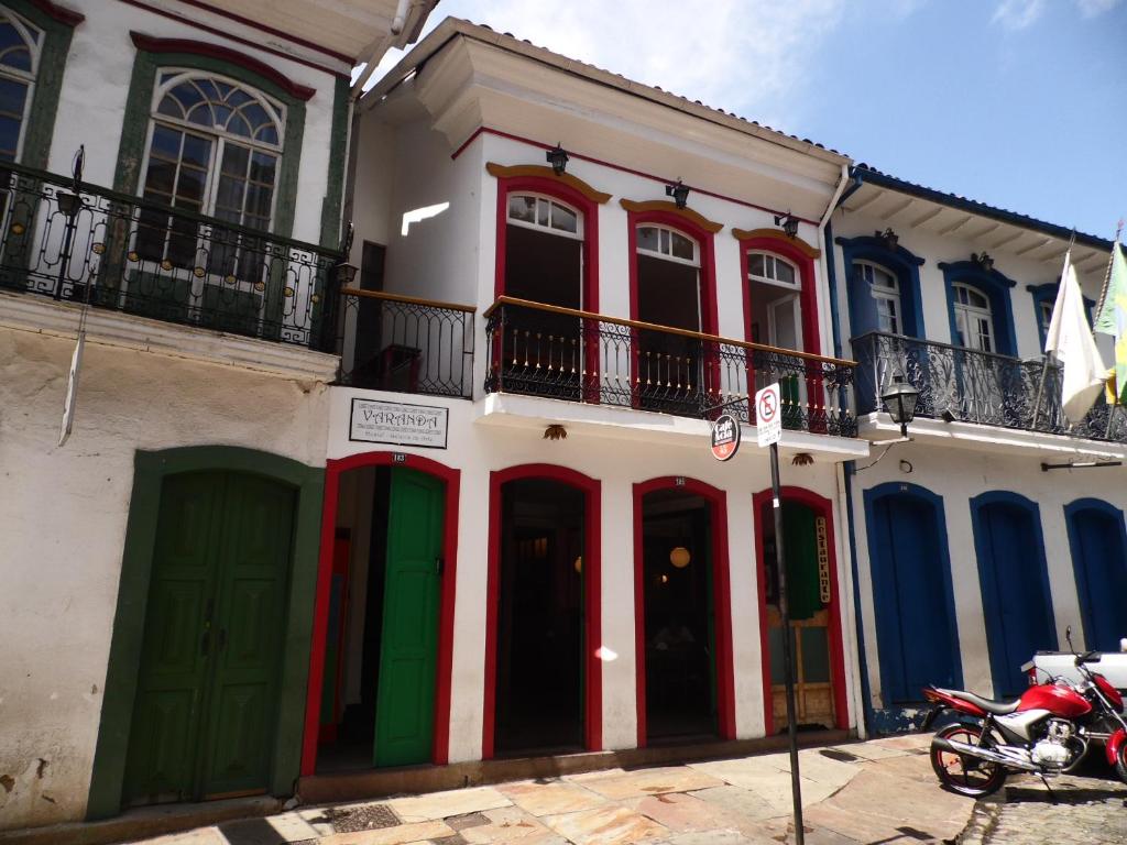 a building with red white and blue doors and a motorcycle at Varanda Hostel E Galeria De Arte in Ouro Preto