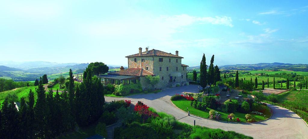 a large building on a hill with trees and flowers at Relais Todini in Collevalenza