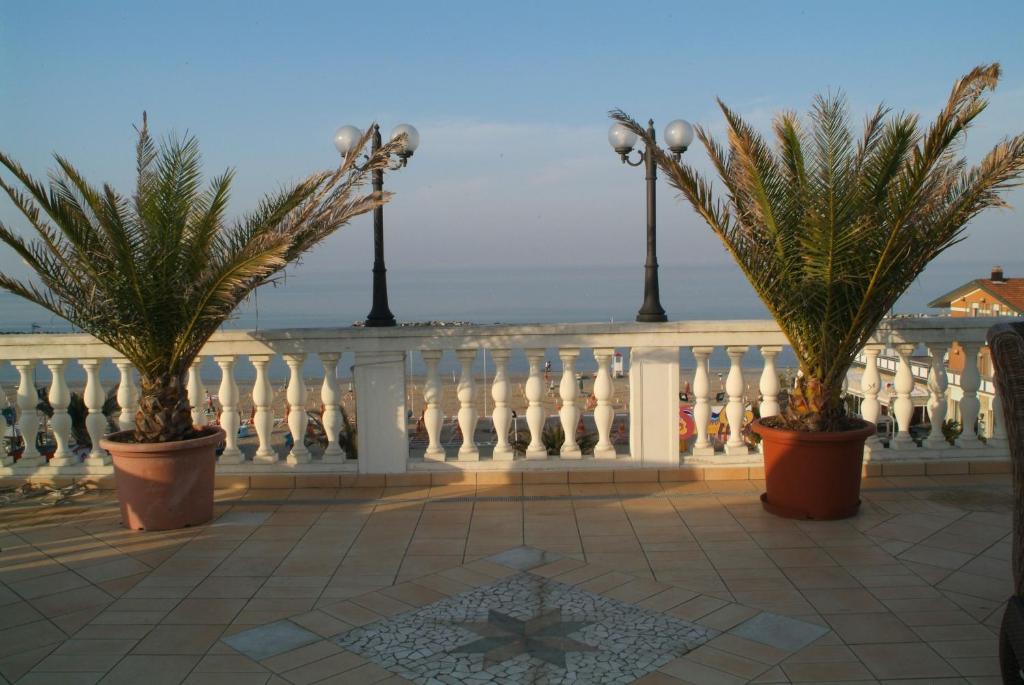 un balcón con palmeras y una valla blanca en Residenza Mediterranea Apartments, en Rímini