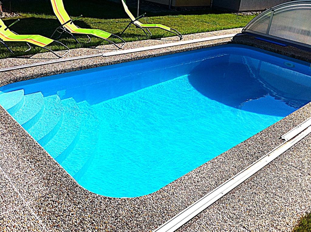 a blue swimming pool with some chairs in it at Apartmány Vojta in Telč