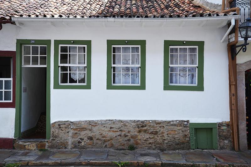 une maison blanche et verte avec des fenêtres vertes dans l'établissement Casa de Rosa, à Ouro Preto