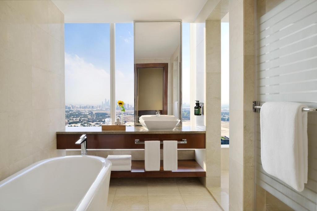 a bathroom with a tub and a sink and a window at voco Dubai by IHG in Dubai