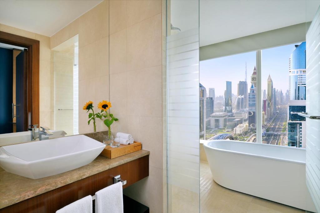 a bathroom with a sink and a tub and a window at voco Dubai by IHG in Dubai