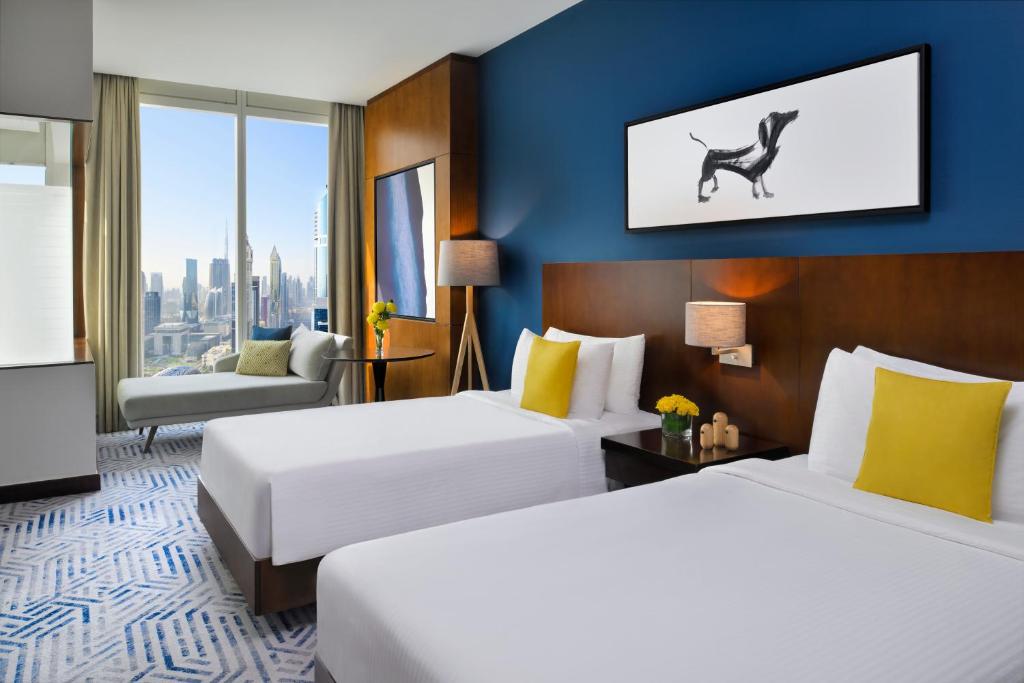 two beds in a hotel room with a dog on the wall at voco Dubai by IHG in Dubai