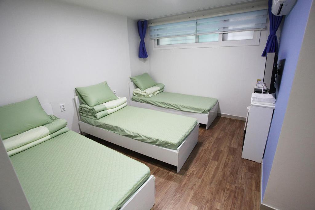 a room with two beds and a tv in it at Namsan Guesthouse in Seoul