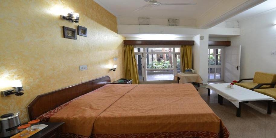 a bedroom with a large bed and a living room at Tilyar Hotel And Resort in Rohtak