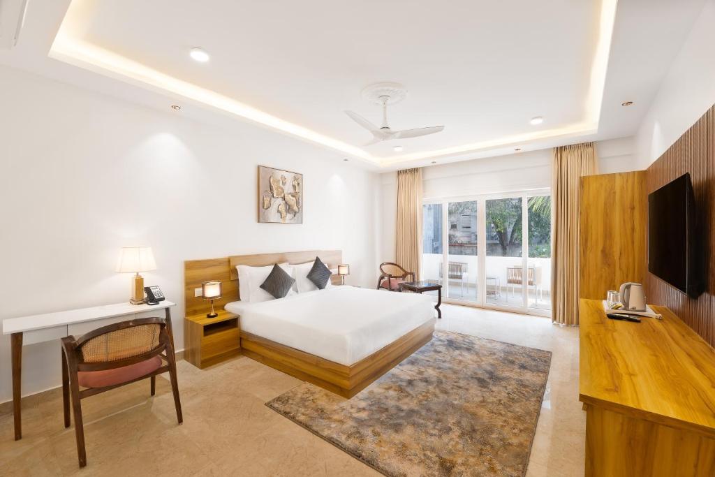 a hotel room with a bed and a television at White Wharf Beach Resort Morjim Goa in Morjim