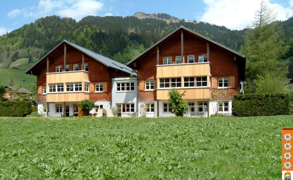 ein großes Gebäude auf einem Feld vor einem Berg in der Unterkunft Ferienwohnungen Erath in Schoppernau