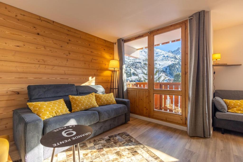 un salon avec un canapé et une grande fenêtre dans l'établissement Renovated Design Apartment with Slopes View Méribel Mottaret, à Les Allues