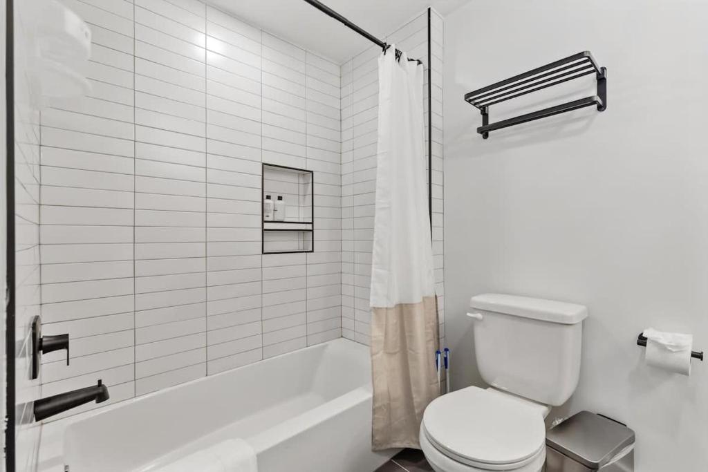 a white bathroom with a toilet and a bath tub at NoMa Convenience 2-BR Near Metro Union Market in Washington, D.C.