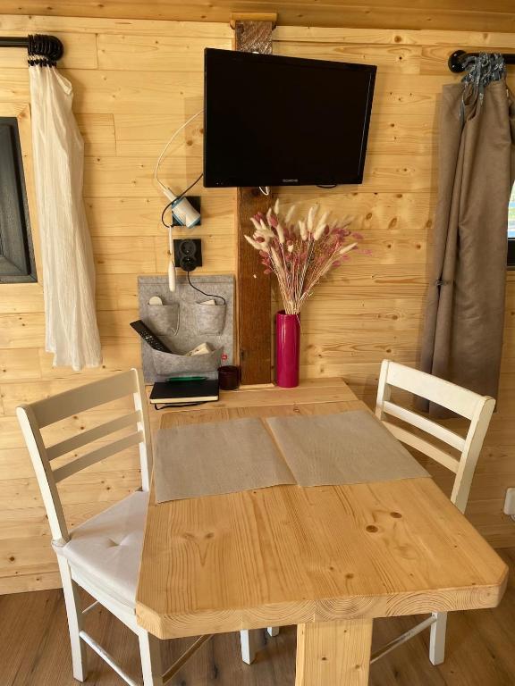 une table et des chaises en bois avec une télévision murale dans l'établissement cabane, à Saint-Vincent-de-Paul