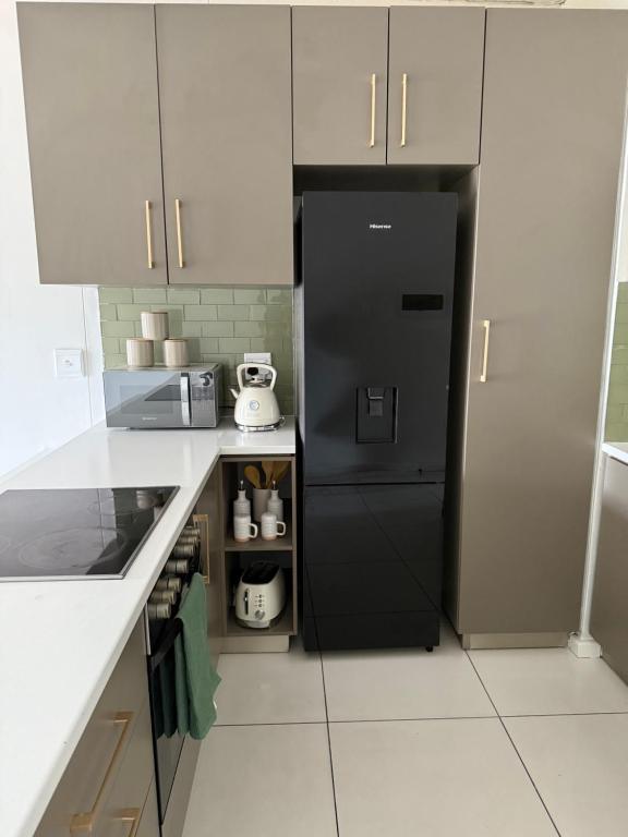 a kitchen with a black refrigerator and white cabinets at Vijas Haven in Windhoek