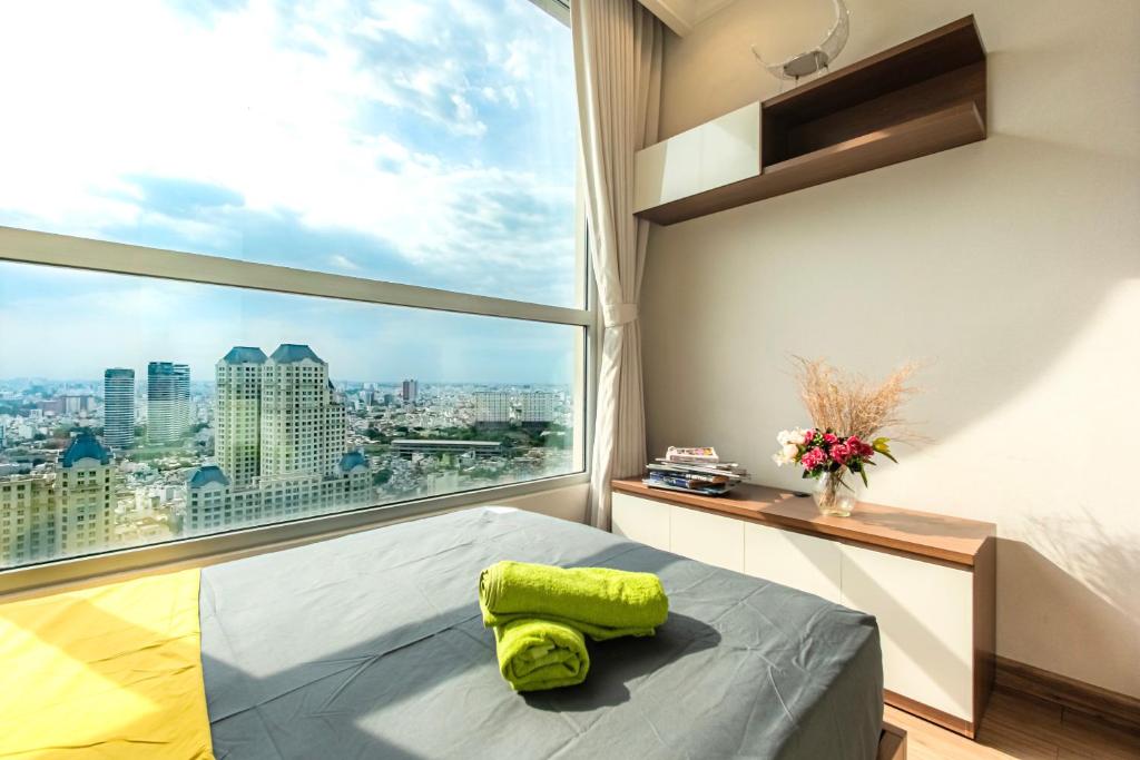 a bedroom with a large window and a bed with a green pillow at Central Apartments - Vinhomes Central Park, Landmark 81 Area & Ice Skating Rink in Ho Chi Minh City