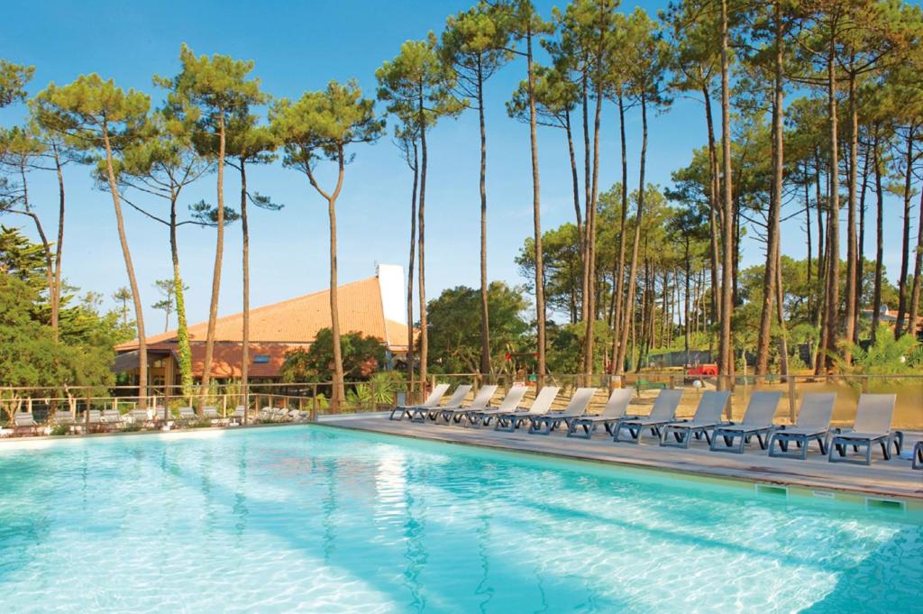 - une piscine bordée de chaises et de palmiers dans l'établissement Résidence Vacances Bleues Domaine de l'Agréou, à Seignosse