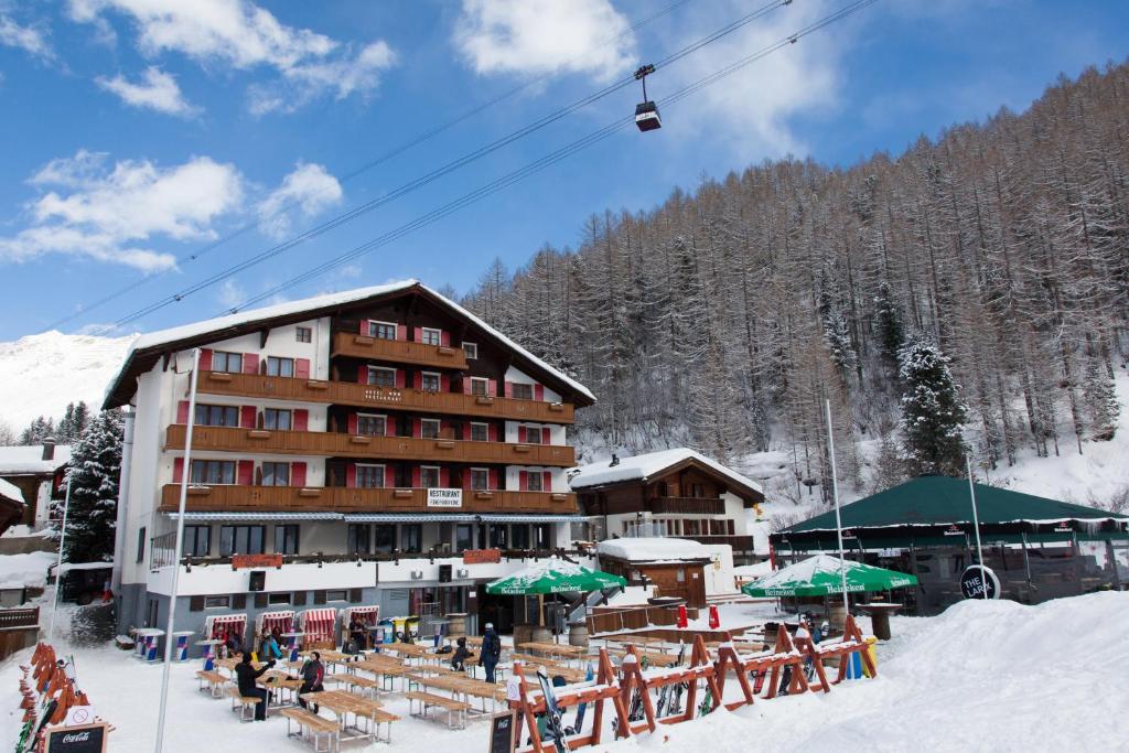 a ski lodge in the snow with a ski lift at Hotel THE LARIX ski-in ski-out in Saas-Fee
