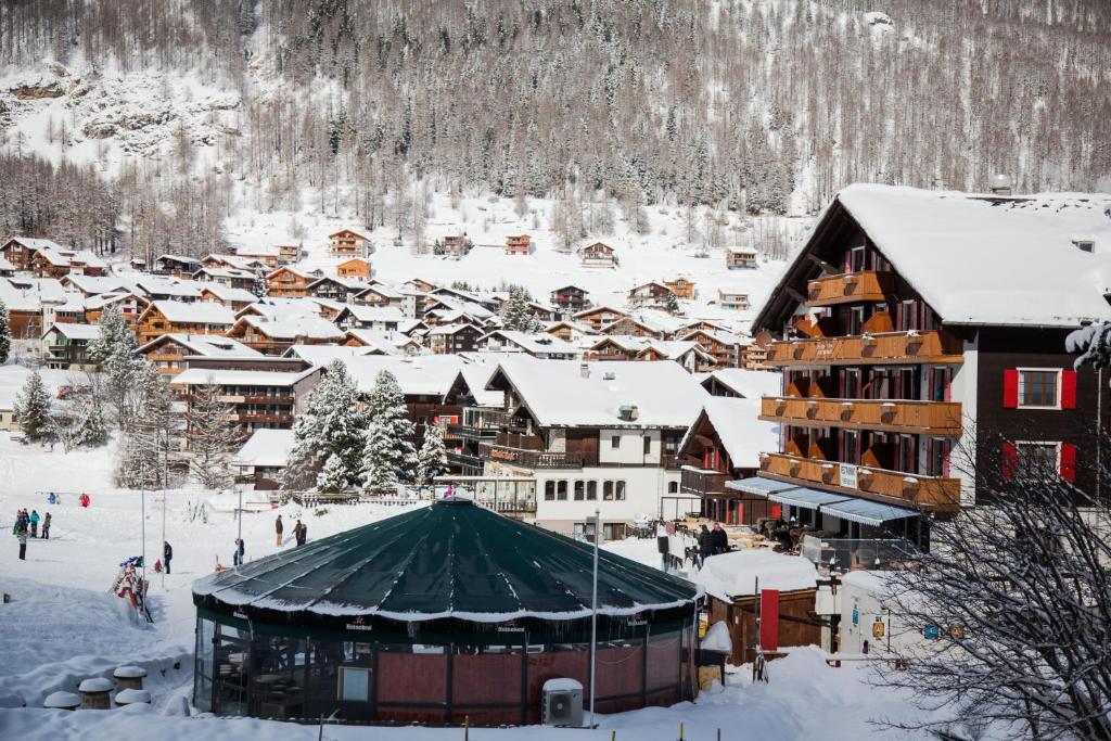 a town covered in snow with a mountain in the background at Hotel THE LARIX ski-in ski-out in Saas-Fee