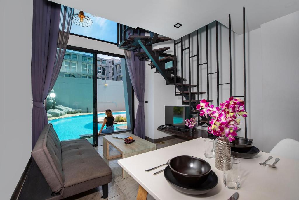a living room with a table and a spiral staircase at Poolside Duplex In Nai harn UTL A102 in Rawai Beach