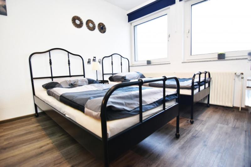 two beds in a room with two windows at Work & Stay Boardinghouse in Solingen in Solingen