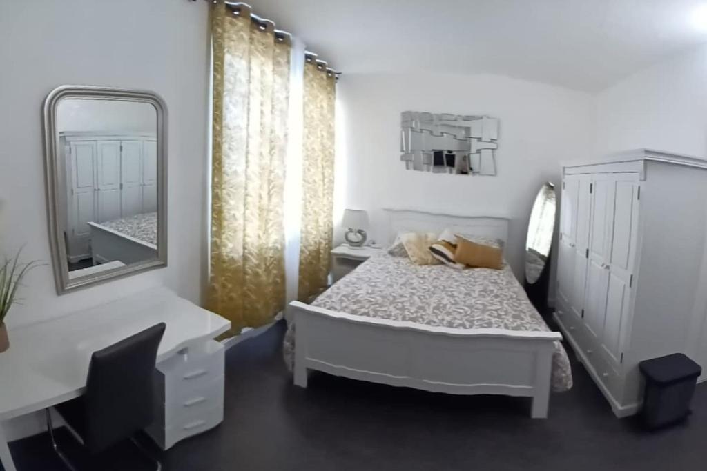 une chambre blanche avec un lit et un miroir dans l'établissement studio le cocon urbain, au Havre