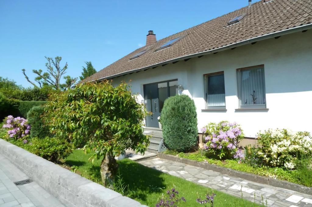 een wit huis met wat struiken en bloemen bij Ferienwohnung Casa Marlies In Daun in Daun