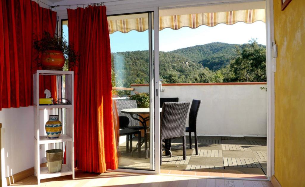 une terrasse avec des rideaux rouges, une table et des chaises dans l'établissement Le Panorama, à Argelès-sur-Mer