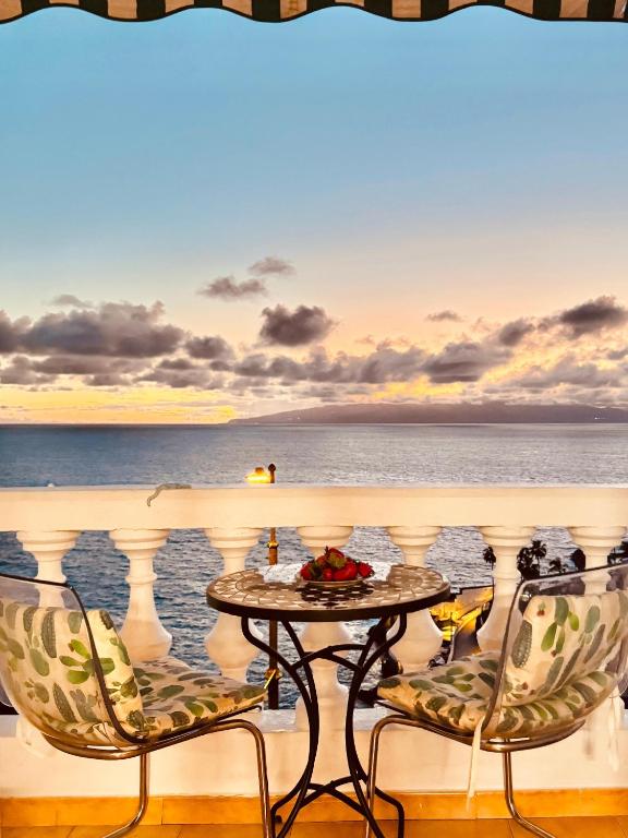 a table and chairs on a balcony overlooking the ocean at Sunset apartment in Puerto de Santiago