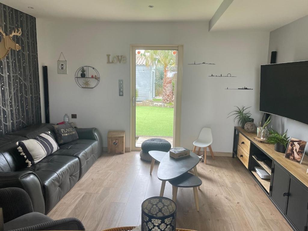 un salon avec un canapé en cuir noir et une table dans l'établissement Maison de campagne avec piscine, à Fors