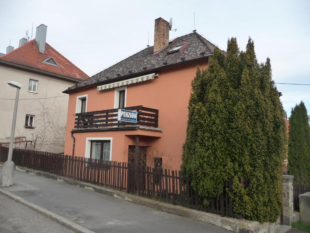 a pink house with a fence and trees at Penzion Zavodsky in Český Krumlov