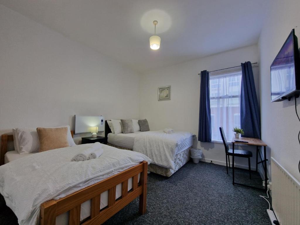 a bedroom with two beds and a flat screen tv at Nice Living Serviced Accommodations 12 in Coventry