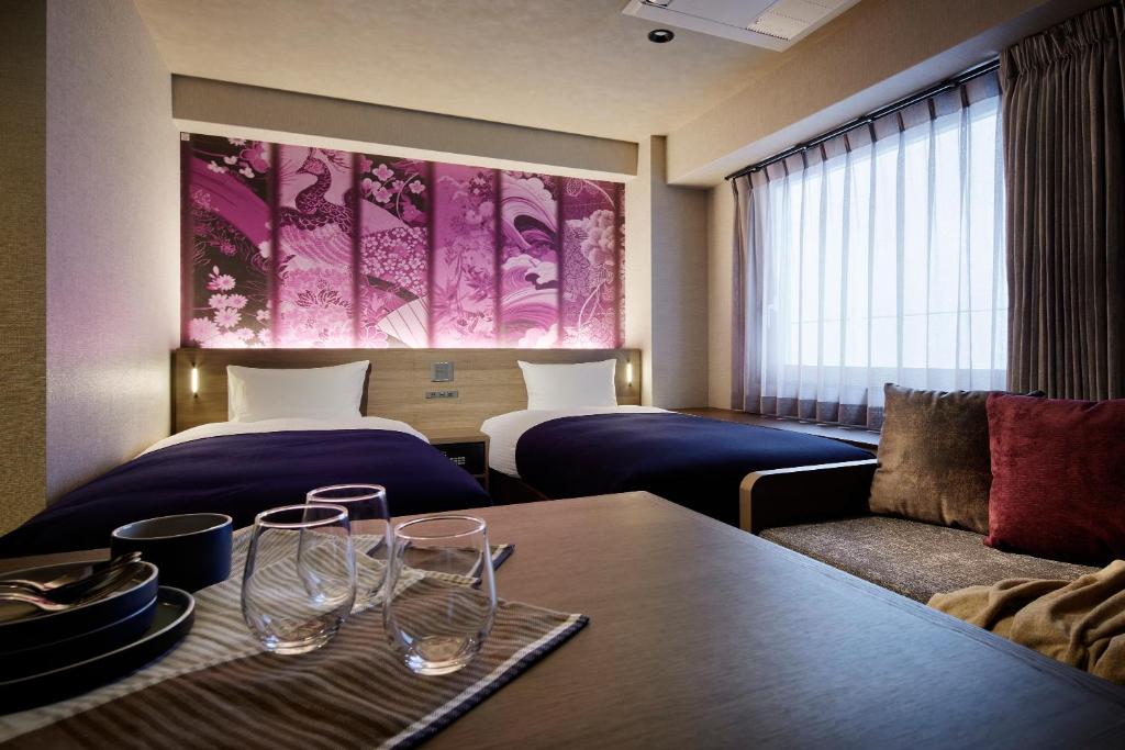 ein Hotelzimmer mit 2 Betten und einem Tisch mit Weingläsern in der Unterkunft Minn Gion Kamogawa in Kyoto