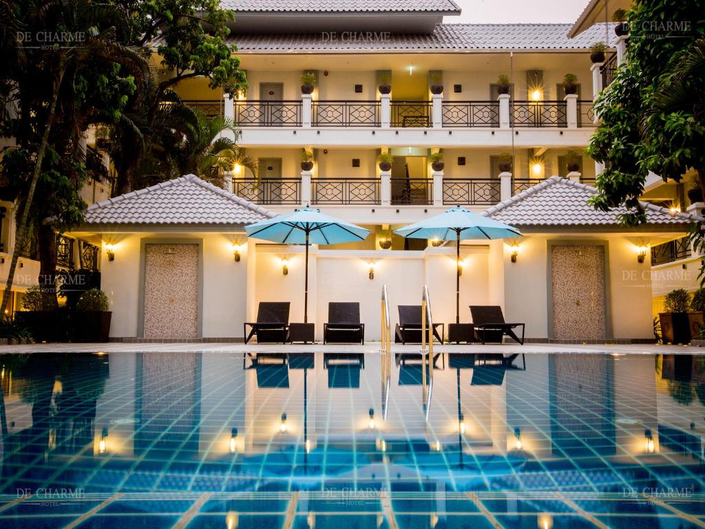 ein Hotel mit einem Pool mit Stühlen und Sonnenschirmen in der Unterkunft Decharme Hotel-SHA Plus in Chiang Mai
