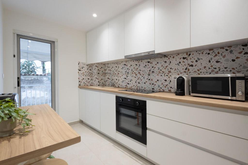 a kitchen with white cabinets and a microwave at Seaside Elegance Brand New 2BD Luxury Stay in Athens