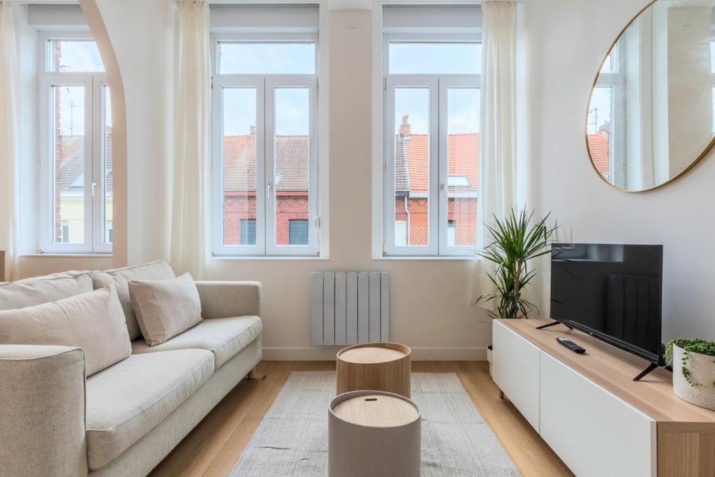 een woonkamer met een bank en een tv bij Appartement T2 proche tramway et commodités in Tourcoing