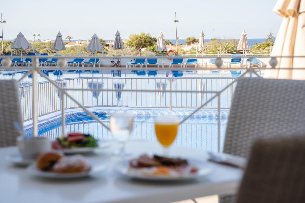 a table with two plates of food and a glass of orange juice at Minura Sur Menorca in Punta Prima
