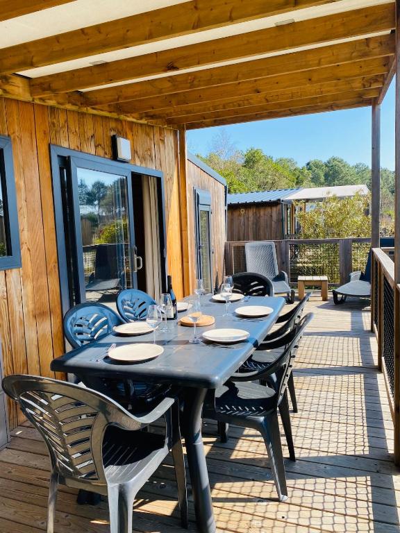 une table noire et des chaises sur une terrasse dans l'établissement Chalet du Bassin Arcachon - Camping Parc aquatique, à Gujan-Mestras