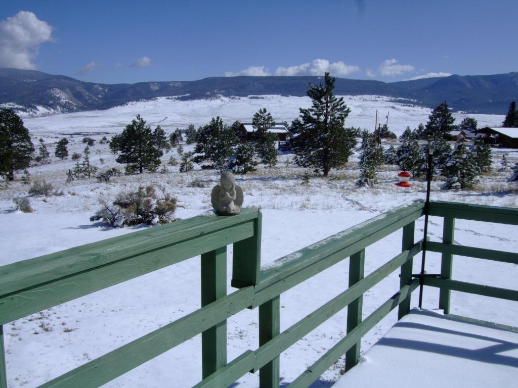 a teddy bear sitting on a fence in the snow at Rainbow House in Angel Fire