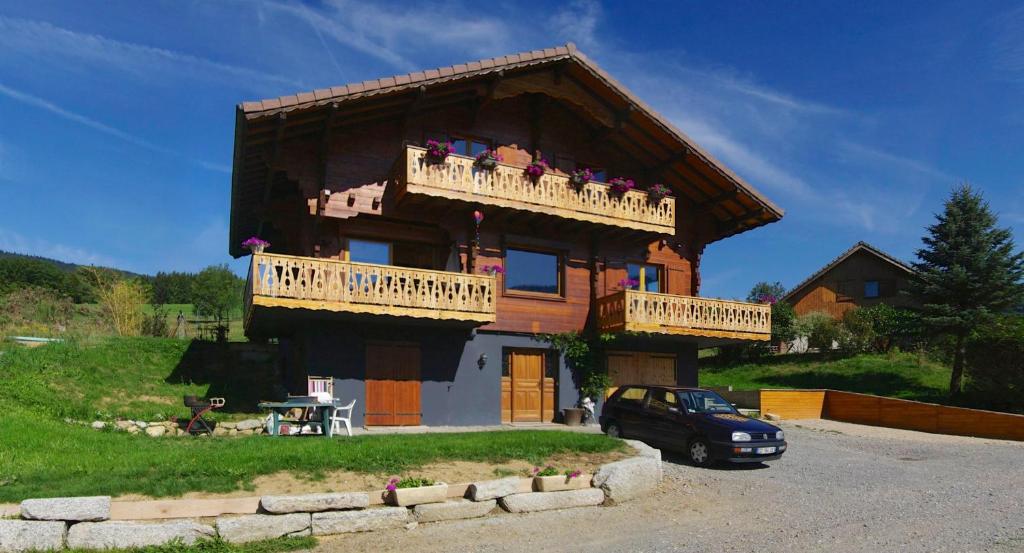 a large wooden house with a balcony and a car at Chalet de Meyje in Habère-Lullin