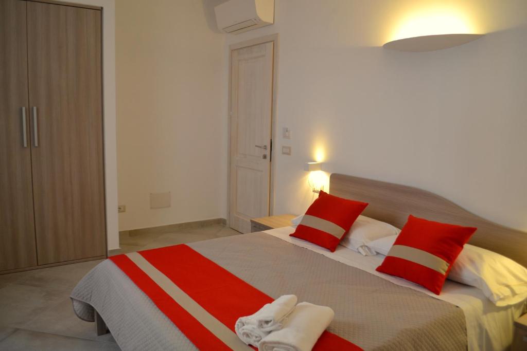 een slaapkamer met een groot bed met rode en witte kussens bij Domo e Sorres in Olbia