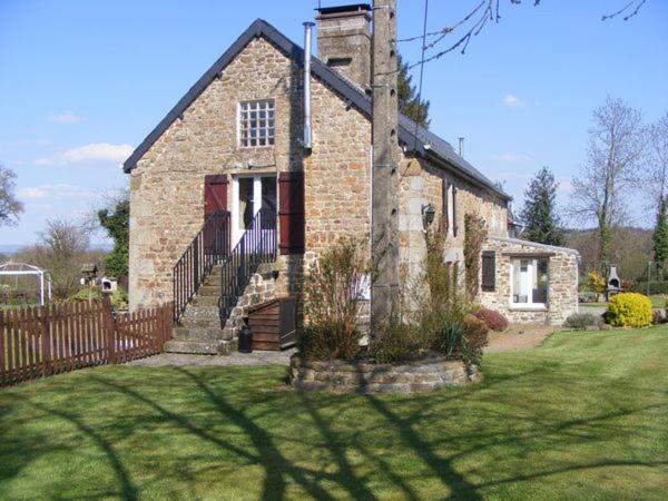 an old brick house with a fence in a yard at La Bannerie in Mesnil-Clinchamps