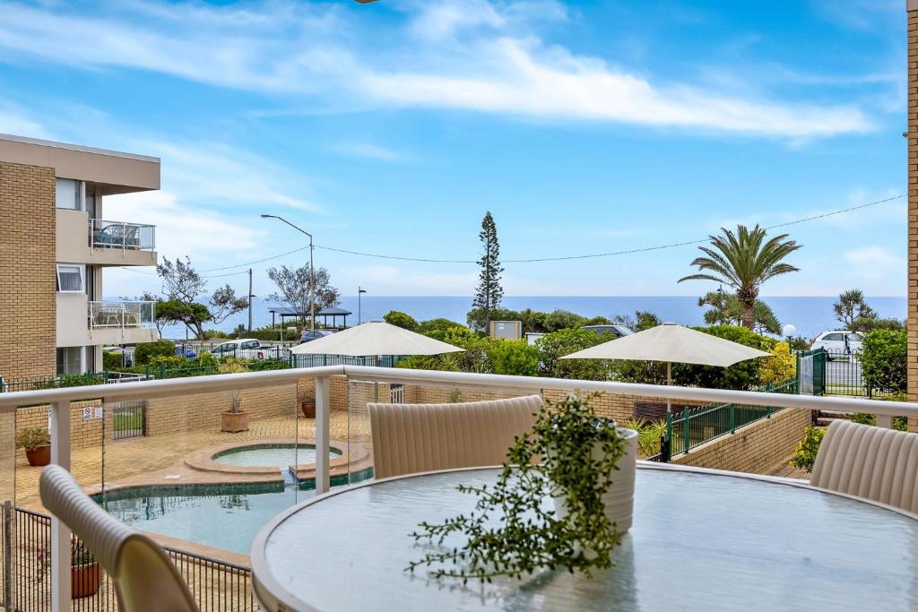 a balcony with a table and chairs and a pool at Headlands 10 Two Bedroom Beachside Apartment with Magical Ocean Views Great Value for Money in Alexandra Headland