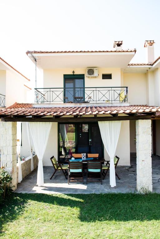 a patio with a table and chairs in front of a house at Maisonette with sea and mountain view !!! in Kriopigi