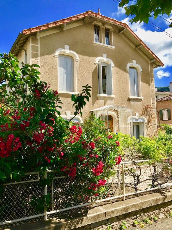 une maison avec des fleurs rouges devant elle dans l'établissement Clair Matin - Appartement Balcon - Maison privée, à Lamalou-les-Bains