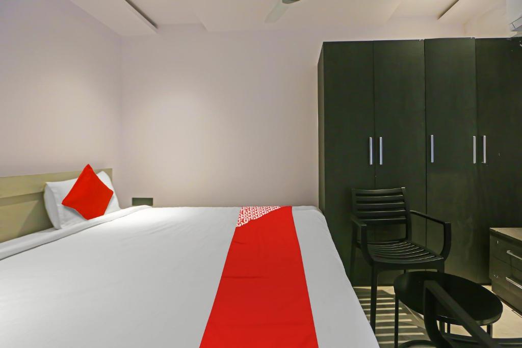 a bedroom with a bed and a chair and a cabinet at Super Hotel O Botcha Convection in Visakhapatnam