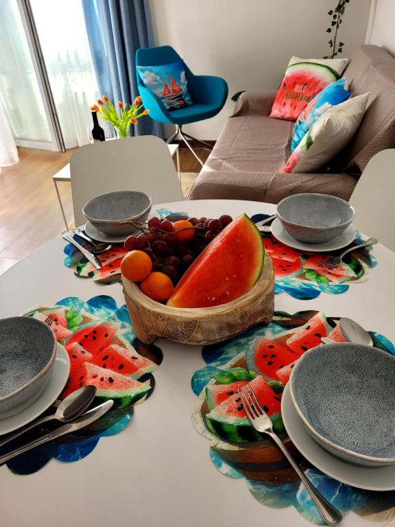 a table with plates and a bowl of fruit on it at Apartament Arbuzowy Zachód Słońca in Pobierowo
