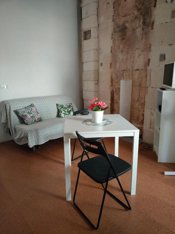 une table blanche et une chaise dans une chambre avec un canapé dans l'établissement Studio Romarin au pied des Arènes, à Arles