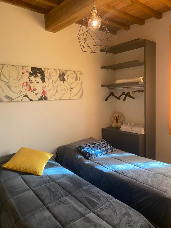 UsiglianoにあるLa casa giallaのベッドが2つあり、壁に絵が飾られた寝室