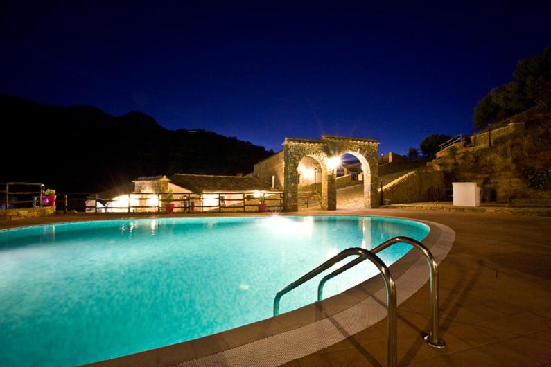 een groot zwembad 's nachts met een gebouw bij Casale Del Golfo in Castellammare del Golfo