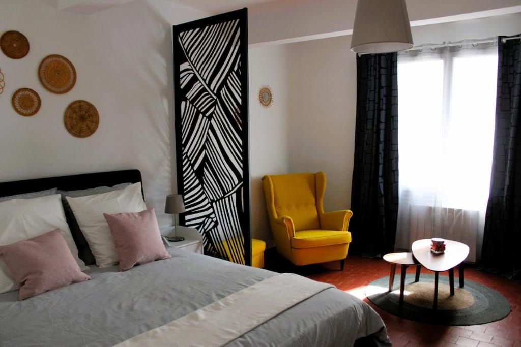 - une chambre avec un lit et une chaise jaune dans l'établissement Appartement Centre Historique, à LʼIsle-sur-la-Sorgue