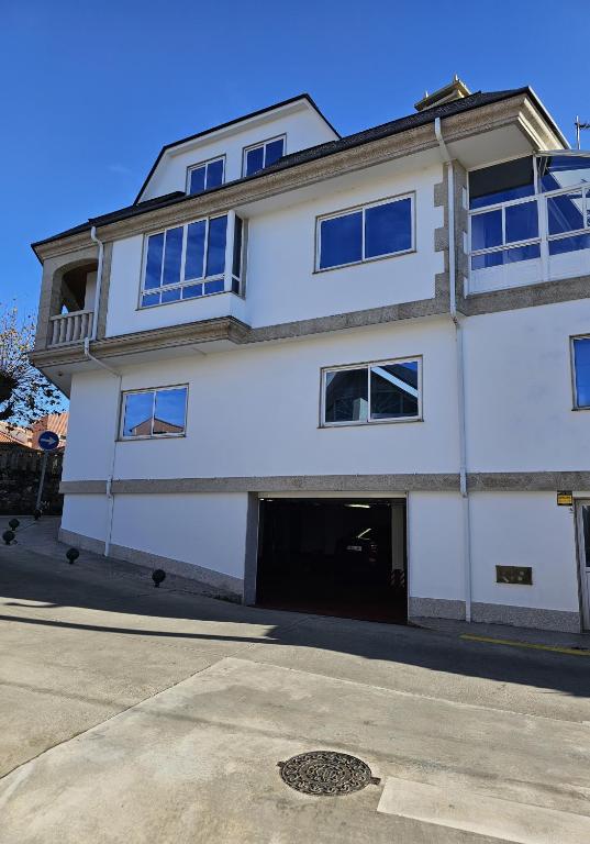 a white building with a garage at Apartamento Priorato in Isla de Arosa